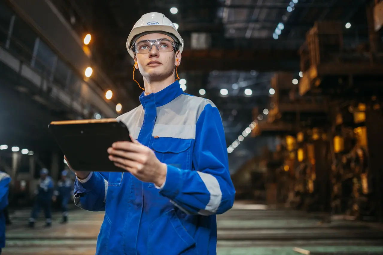 Operario con casco y tableta supervisando una planta