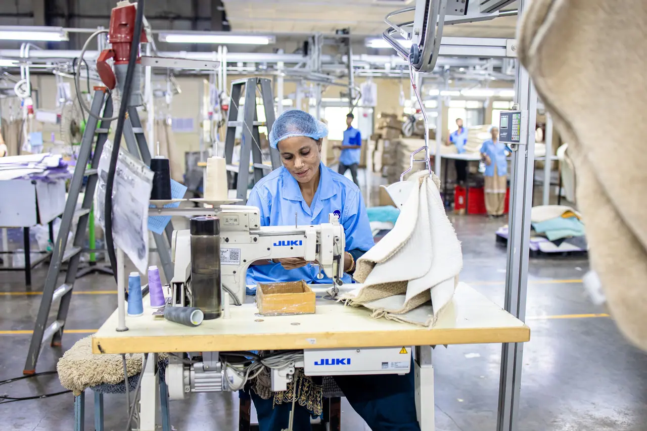 Operaria cosiendo en una planta de confección textil